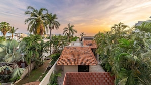 A residential area with terracotta-tiled roofs, palm trees, and a clear sky. - Chiapas boutique apartment (Bucerías)