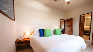 A bedroom with a large bed, a bedside table with a lamp, and a wooden wardrobe. - Chiapas boutique apartment (Bucerías)