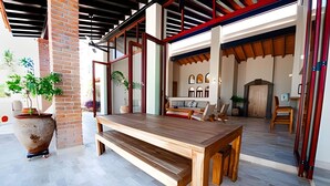An open-plan living area with a wooden dining table, benches, and a large potted plant. - Casa Riviera complex with 3 pools (Bucerías)