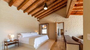 A bedroom with a wooden ceiling, a bed, a nightstand, a desk, and a view through a window. - Casa Riviera complex with 3 pools (Bucerías)