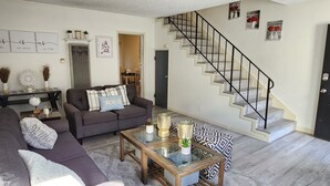 Un salon avec un canapé, une table basse et un escalier.