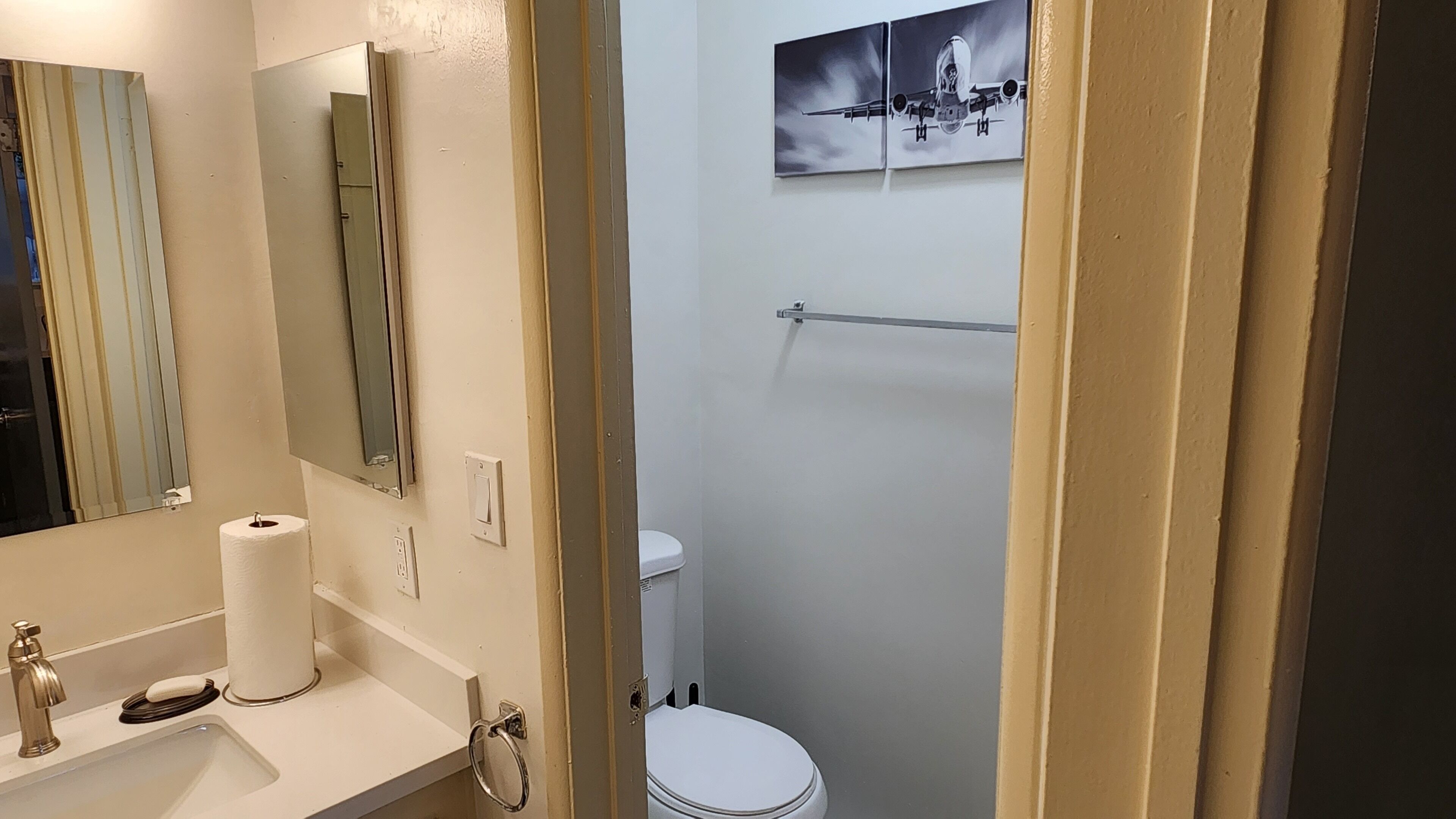 A bathroom with a sink, mirror, toilet, and towel rack.
