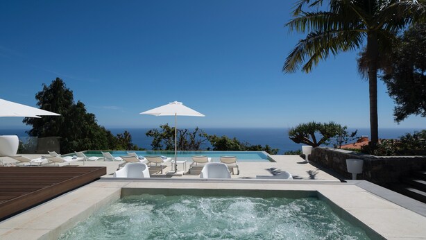Un bain à remous avec vue sur l’océan, entouré de chaises longues et de parasols.
