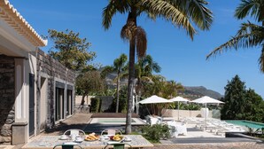 Une terrasse avec une table préparée pour le petit-déjeuner, des sièges extérieurs et un espace piscine.