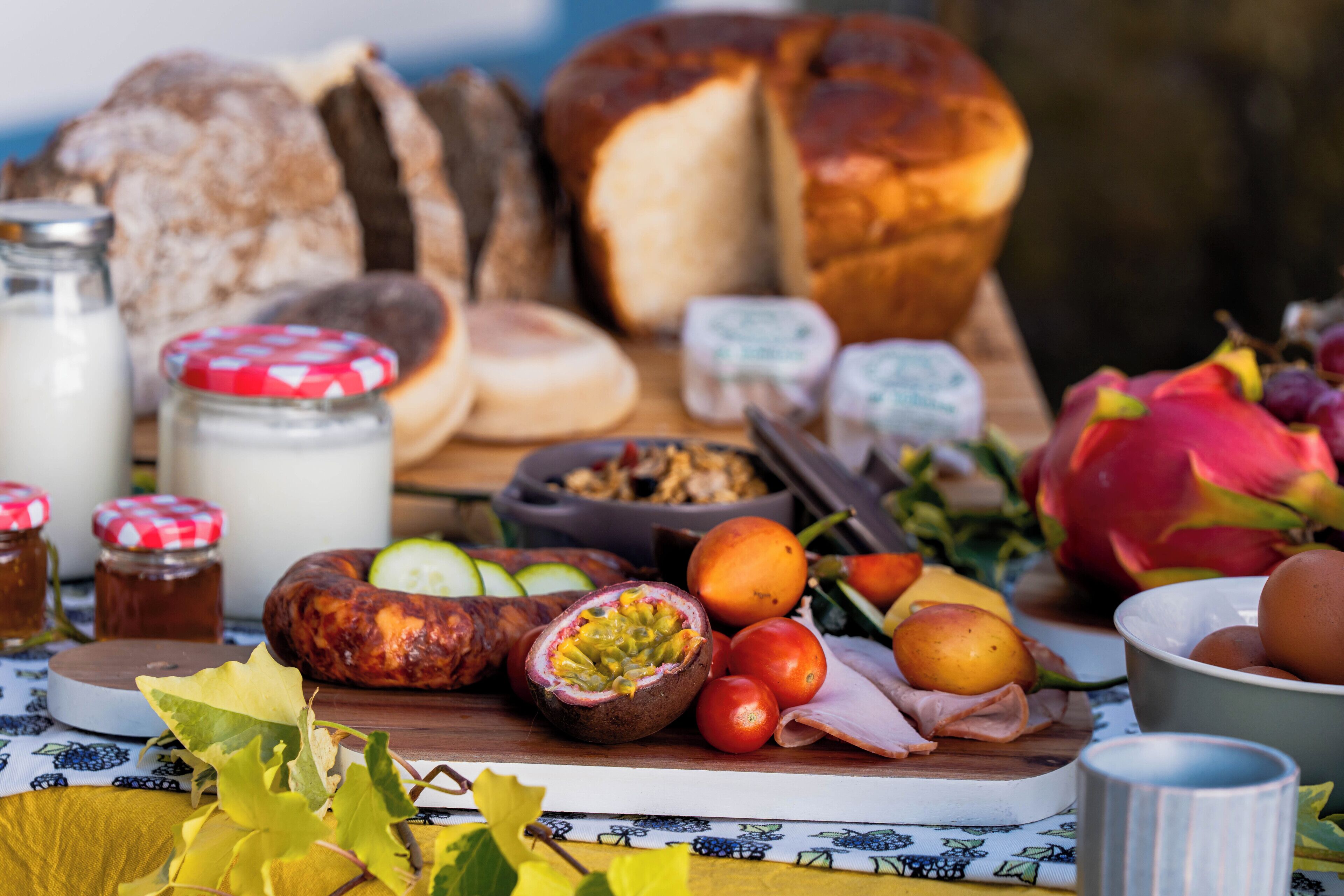 Une variété d’aliments, notamment du pain, du fromage et des fruits, présentés sur une planche en bois.