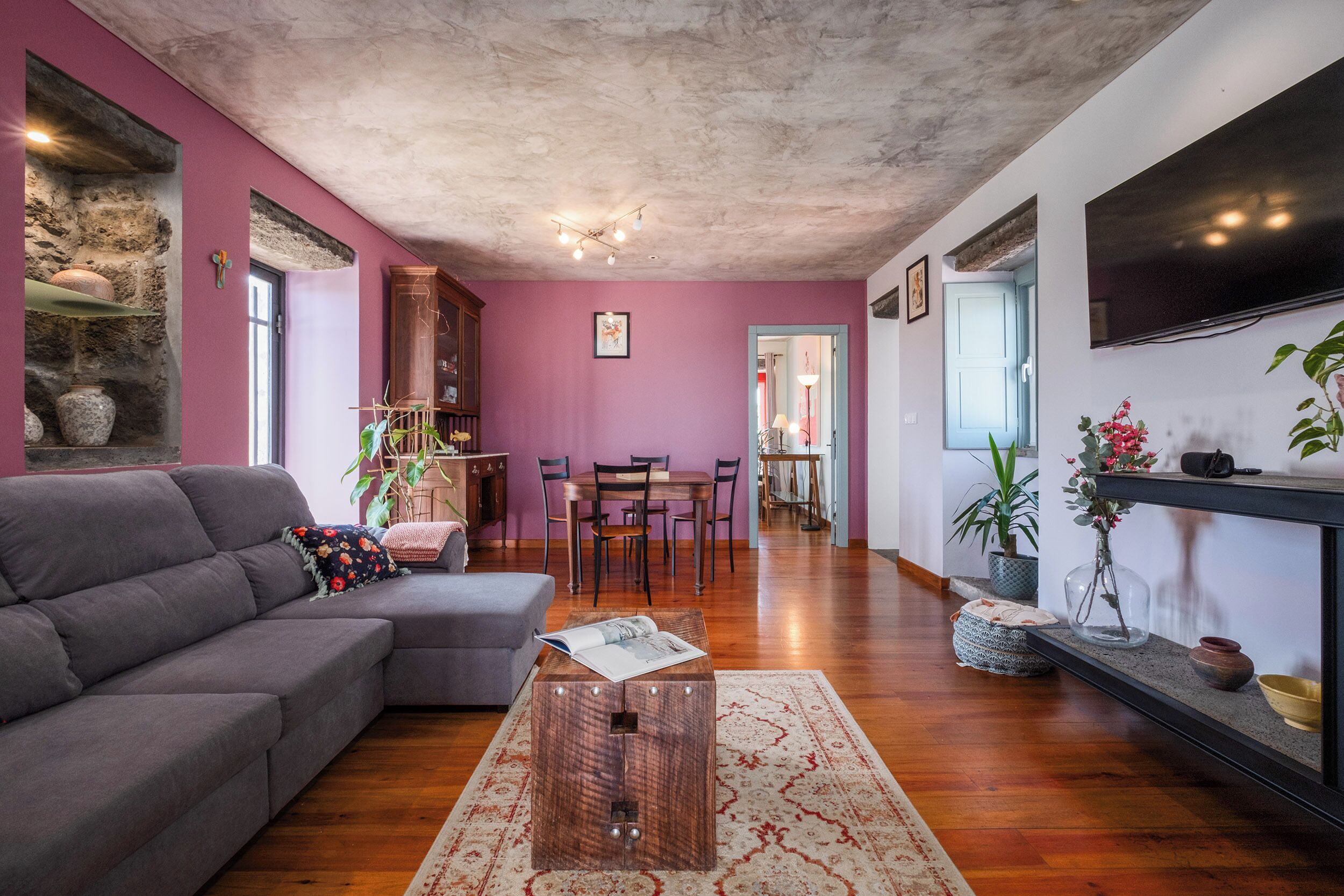 Una sala de estar con un sofá gris, una mesa de centro de madera y un comedor con una mesa y sillas.