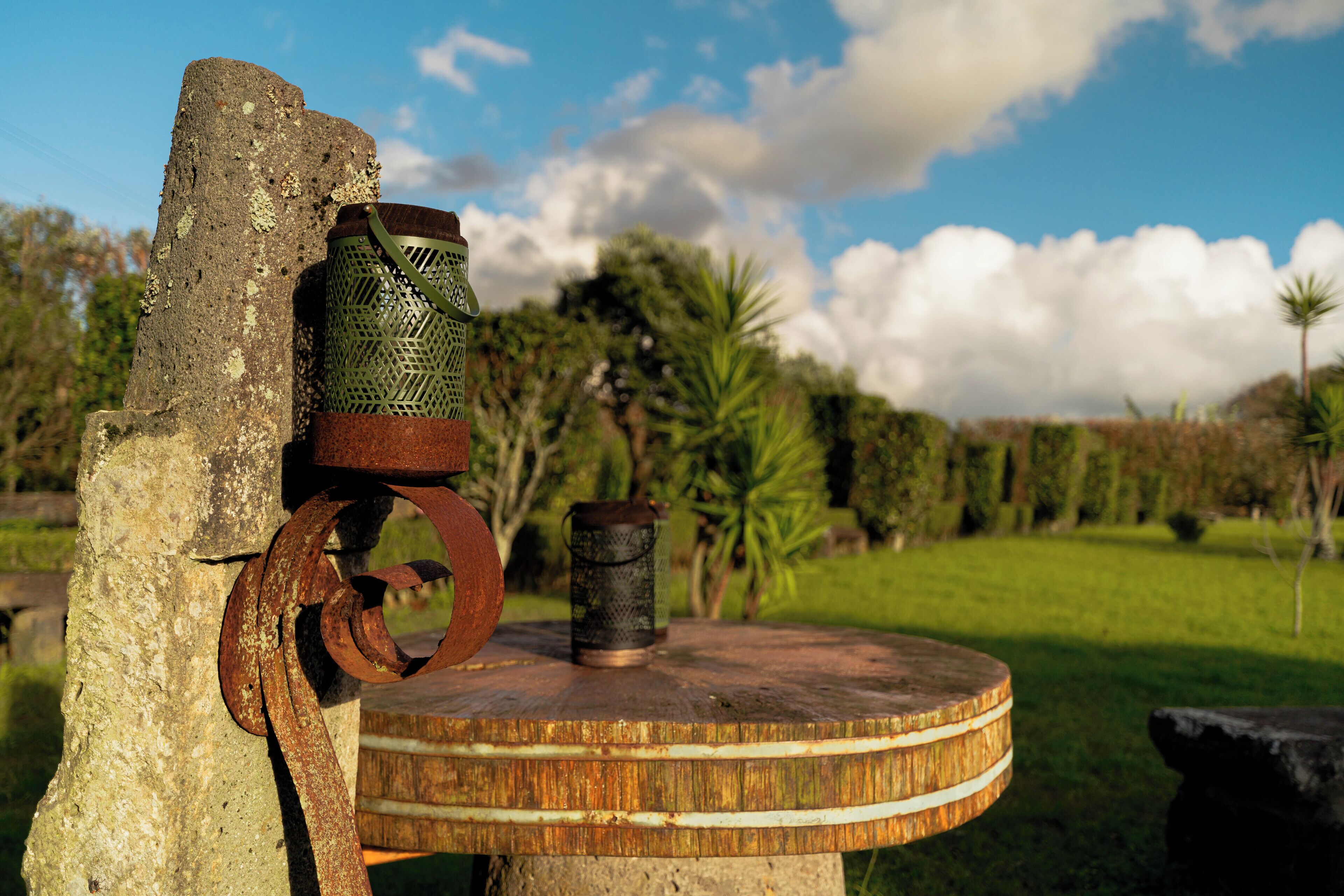 A rustic outdoor setting with a wooden table, a metal object, and a green container.