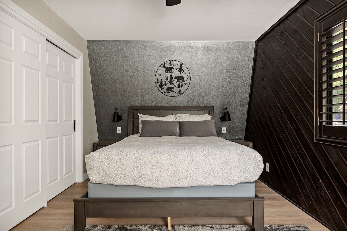 Un dormitorio con cama, una obra de arte circular en la pared y una ventana con persianas.