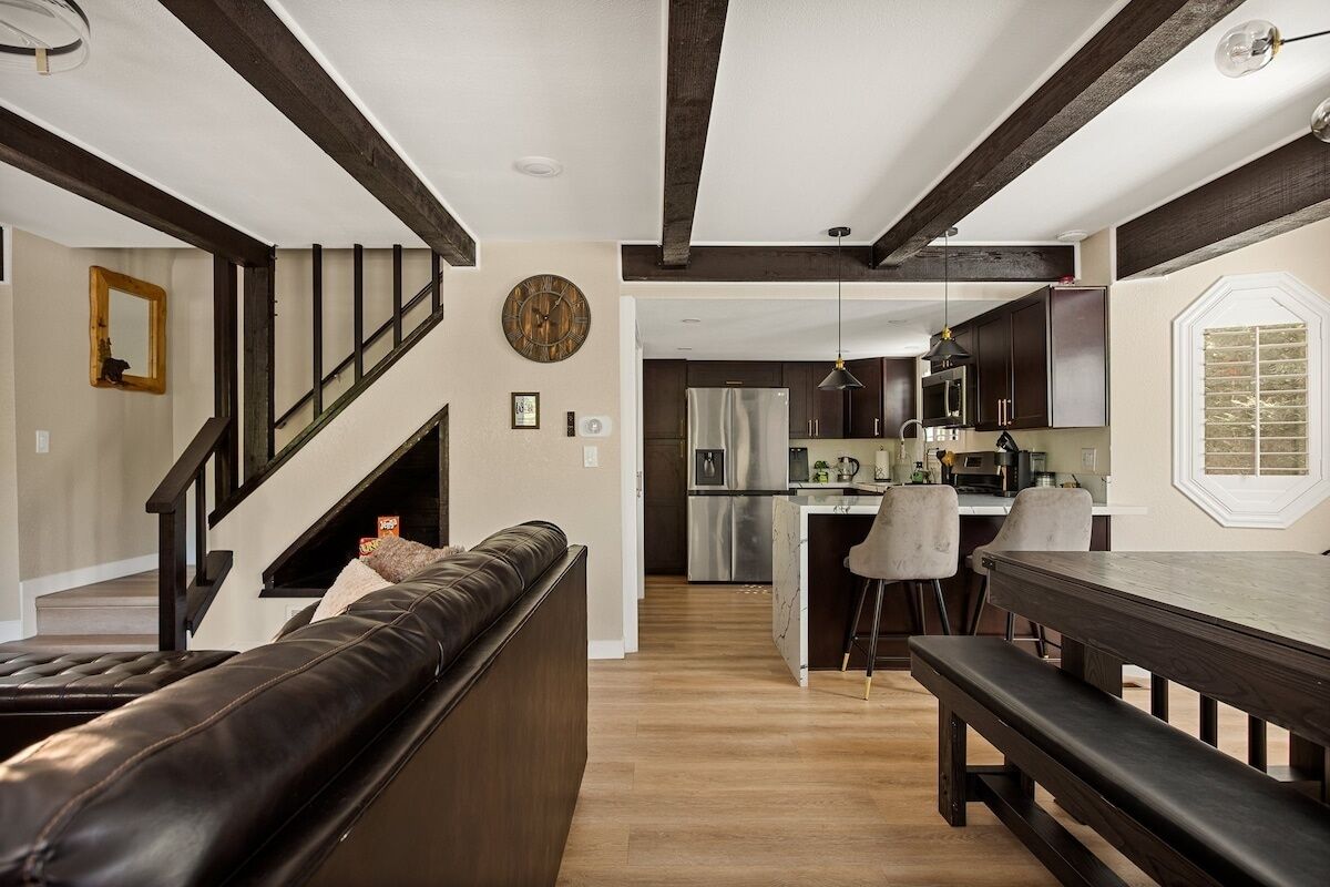 A modern kitchen with dark cabinetry, a central island, and a dining area with a bench.