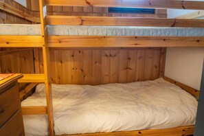 Ein Stockbett mit einem Holzkopfstück und einem Einzelbett darunter.