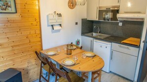 Eine kleine Küche mit Esstisch für vier Personen, einem kleinen Kühlschrank und einer Mikrowelle.