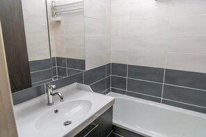 Ein Badezimmer mit einem weißen Waschbecken, einem Spiegel und einer Badewanne.