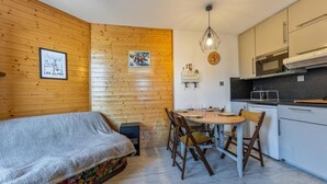 Ein gemütliches Zimmer mit einem Bett, einem Esstisch mit Stühlen, einer Küchenzeile und Holzwänden.