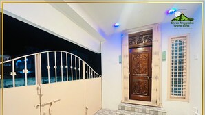 Una entrada protegida por una puerta de madera decorativa y un ventanal con diseño de cuadrícula.