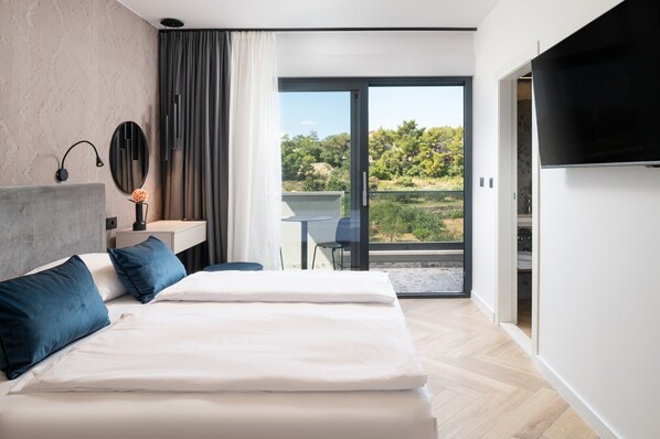 Una habitación de hotel moderna con una cama grande, un escritorio pequeño, una silla y un televisor.