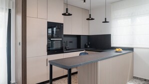 A modern kitchen with a built-in microwave, a coffee machine, and a small island with a bowl of fruit. - Luxury Villa David 1 heated pool 38m2 bbq Seaview (Podstrana)