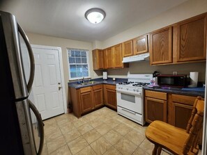 Een koelkast, een magnetron, kookgerei, borden en bestek, keukenrol