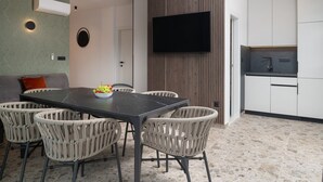 A modern kitchen with a flat-screen TV, a dining area with wicker chairs, and a built-in oven. - Luxury Villa David's two heated pools 38m2 bbq Seaview (Podstrana)