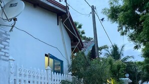 A white building with a satellite dish, a white picket fence, and a dirt road. - Ceylon Beach Haven Uppuveli (Trincomalee)