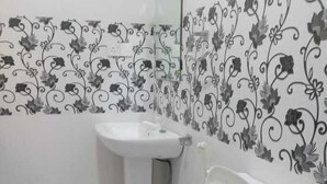 A small bathroom with a toilet, sink, and mirror. - Ceylon Beach Haven Uppuveli (Trincomalee)