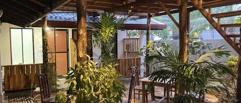 Un espace extérieur aménagé en terrasse, avec des meubles en bois, notamment des chaises et une table, entouré de différentes plantes en pot.