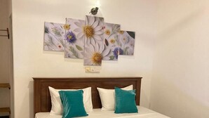 A bedroom with a wooden bed, white and teal bedding, a teal throw blanket, and a floral wall art piece above the bed. - Ceylon Beach Haven Uppuveli (Trincomalee)