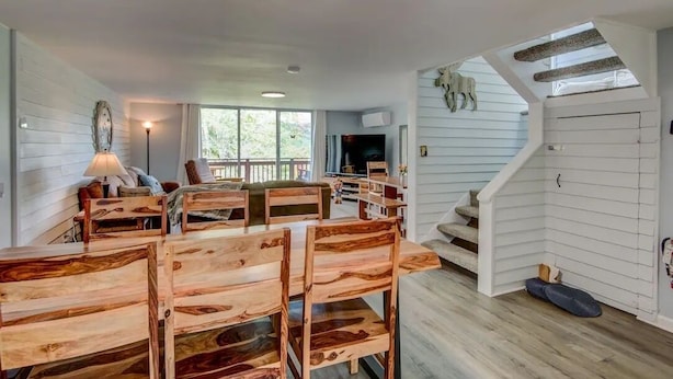 A spacious living area with a wooden dining table and chairs, a sofa, and a staircase leading to an upper level. - 4BR/4Bath Townhome w/AC, Walk to Ski, Golf, Tennis, Hiking and More! (Sugar Mountain)