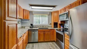 A kitchen with wooden cabinets, stainless steel appliances, a window with blinds, and a countertop with a coffee maker. - 4BR/4Bath Townhome w/AC, Walk to Ski, Golf, Tennis, Hiking and More! (Sugar Mountain)