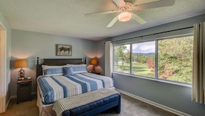 A bedroom with a bed, a nightstand, a bench, a ceiling fan, and a large window with a view of greenery. - 4BR/4Bath Townhome w/AC, Walk to Ski, Golf, Tennis, Hiking and More! (Sugar Mountain)