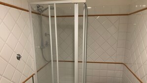 A shower with a glass door, white tiled walls, and a wooden trim. - Sdrucciolo dei Pitti First Floor (Florence)
