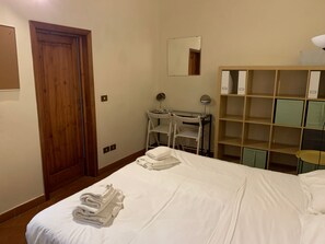 Ein Hotelzimmer mit Bett, Schreibtisch, Stuhl, Spiegel und Kleiderschrank.