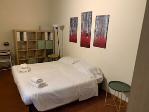Ein Hotelzimmer mit Bett, Nachttisch, Lampe, Schrank und Bildern an der Wand.