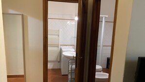 A narrow hallway leading to a bathroom with a toilet, sink, and towel rack. - Sdrucciolo dei Pitti First Floor (Florence)
