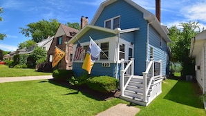 A blue house with a number 410 on the front, a small porch, and a flag. - Updated Bungalow Steps to Notre Dame 410 (South Bend)