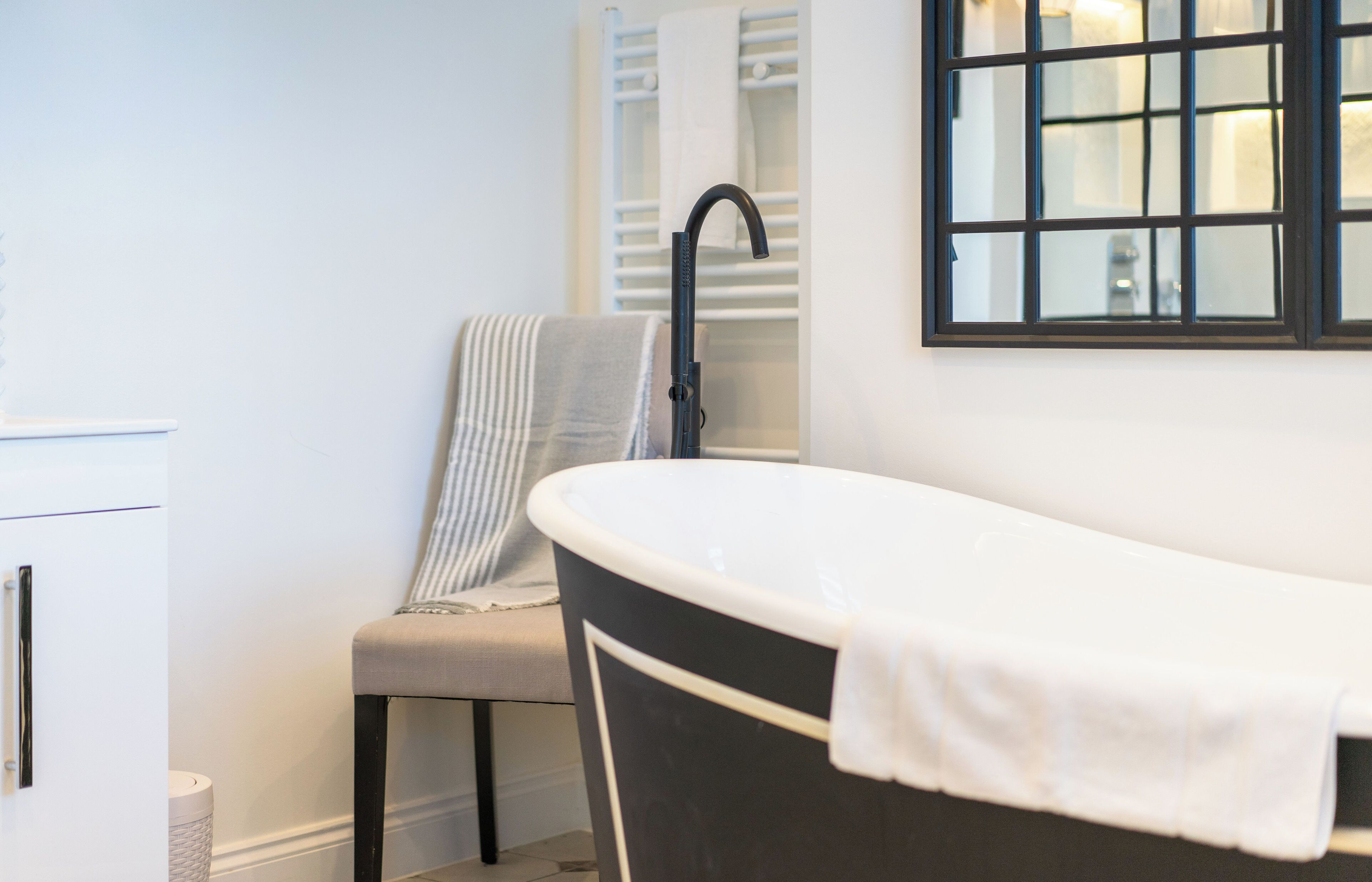 Une salle de bain avec une baignoire sur pieds, un porte-serviettes et une chaise.