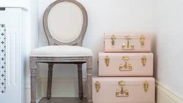A vintage-style chair with a round mirror and three stacked suitcases with brass locks.