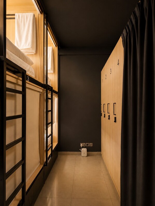 A corridor with bunk beds, a dark wall, and wooden lockers.