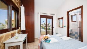 Una habitación de hotel con cama, escritorio, baño y balcón con vistas.