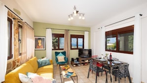 Sala de estar com sofá, televisão, mesa de jantar e cadeiras.