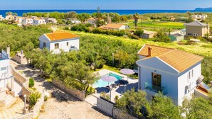 Un quartier résidentiel avec des maisons, une piscine et une vue sur la mer.