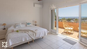 Een slaapkamer met een bed, nachtlampen en uitzicht op het balkon met stoelen.