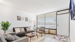Ein modernes Wohnzimmer mit einer Couch, einem Sessel, einem Couchtisch und einer kleinen Pflanze.