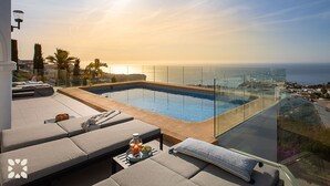 Ein Dachpool mit unendlicher Optik, eine Glastrennwand, Liegestühle und freier Blick auf den Ozean.