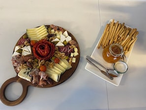 Enjoy a casual gathering with a charcuterie board featuring an assortment of cheeses, meats, nuts, and fresh fruits.