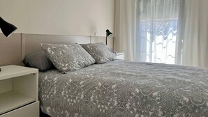 A bedroom with a large bed, two pillows, a bedside table, and a lamp.