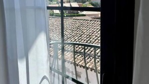 Vista desde un balcón con baranda de metal, una montaña al fondo y un cielo azul despejado.