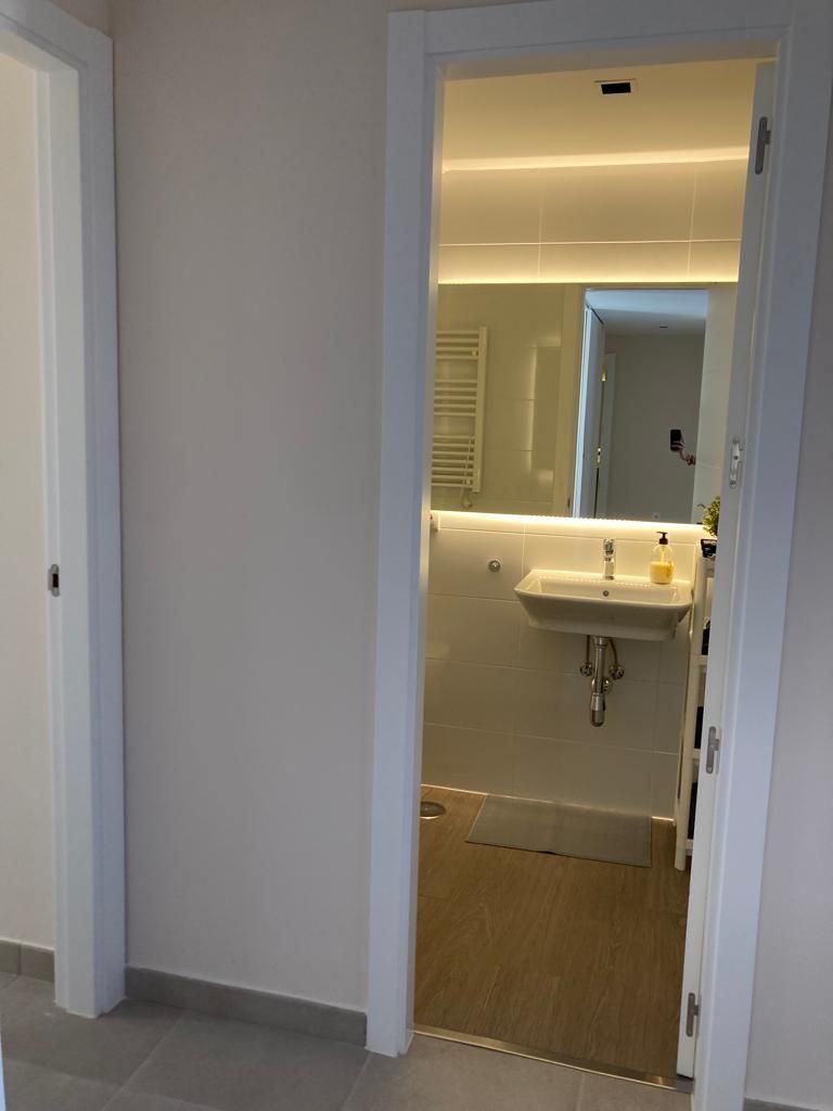 Un baño moderno con lavamanos, espejo y toallero.