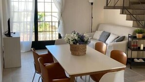 Una sala de estar moderna con comedor, una escalera y vistas al exterior.
