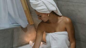 A person sitting in a bathtub with floral arrangements.