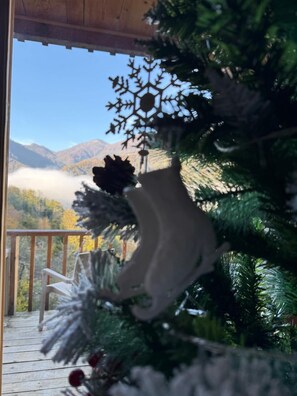 Une terrasse en bois décorée d’un sapin de Noël orné d’un flocon de neige et de pommes de pin.